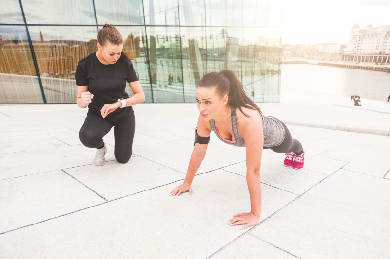 Woman doing push-ups exercises with her personal trainer