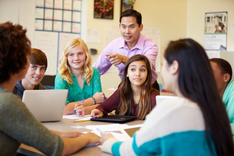 High School Students With Teacher In Class Using Laptops