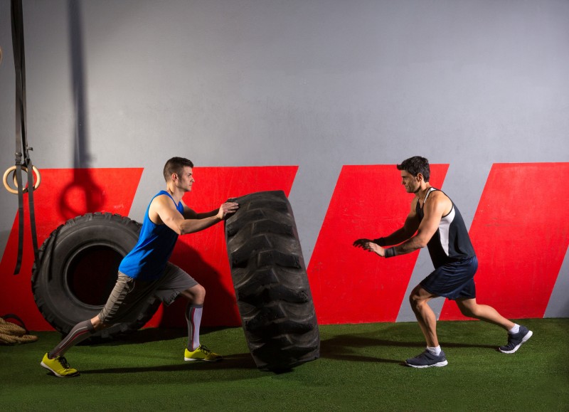 27491246 - men flipping a tractor tire workout exercise at gym