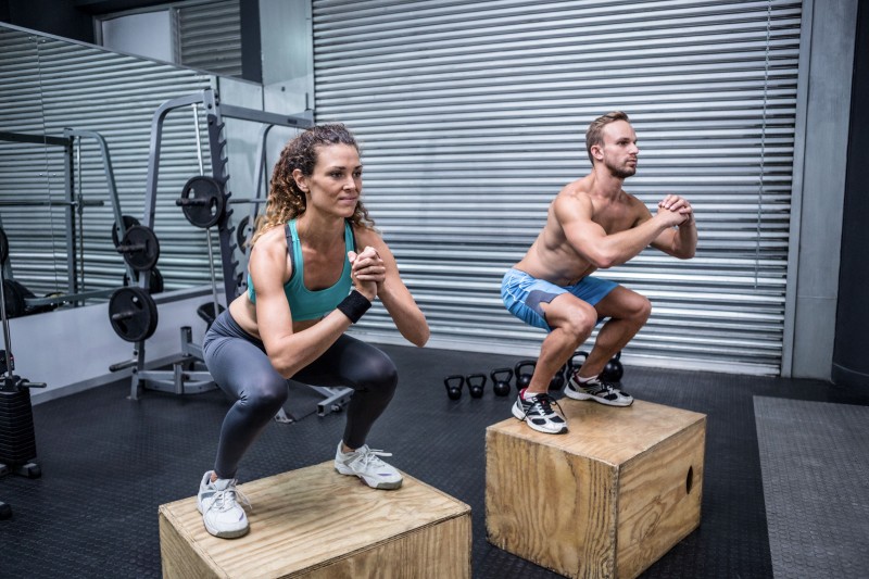 42327116 - muscular couple doing jumping squats on a wooden box