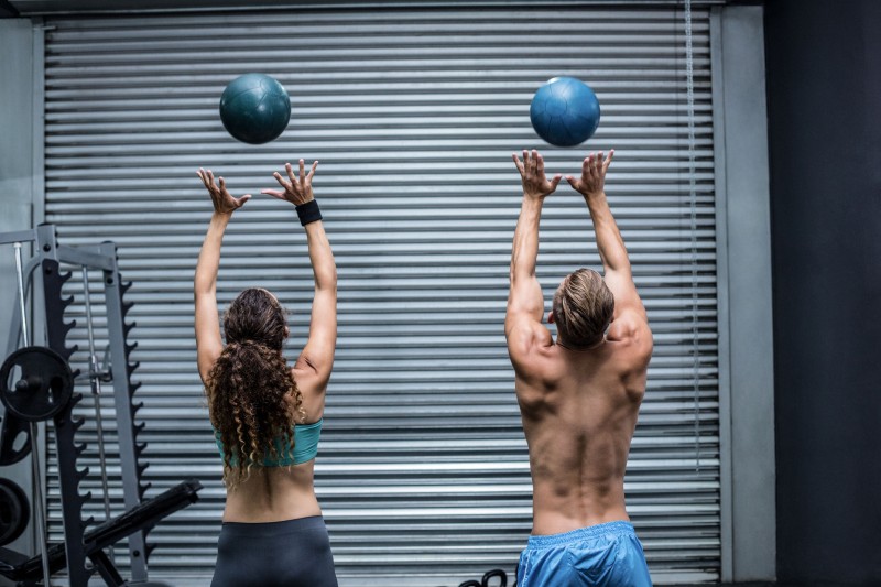 42327141 - back view of a muscular couple throwing ball in the air