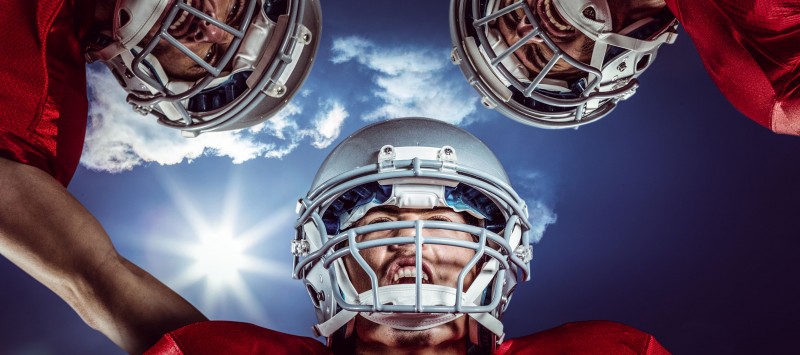 67355542 - 3d american football huddle against bright blue sky with clouds