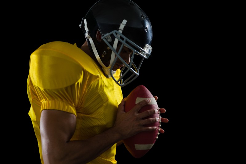 American football player holding a football with both his hands