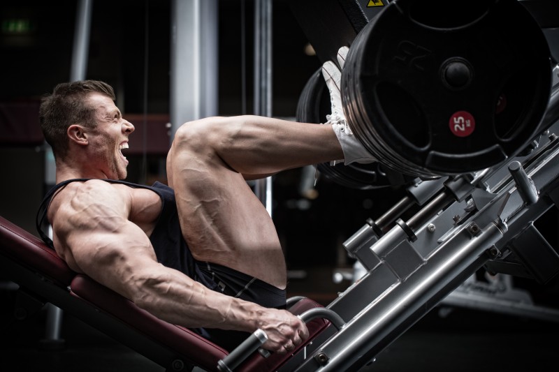 Man in gym training at leg press