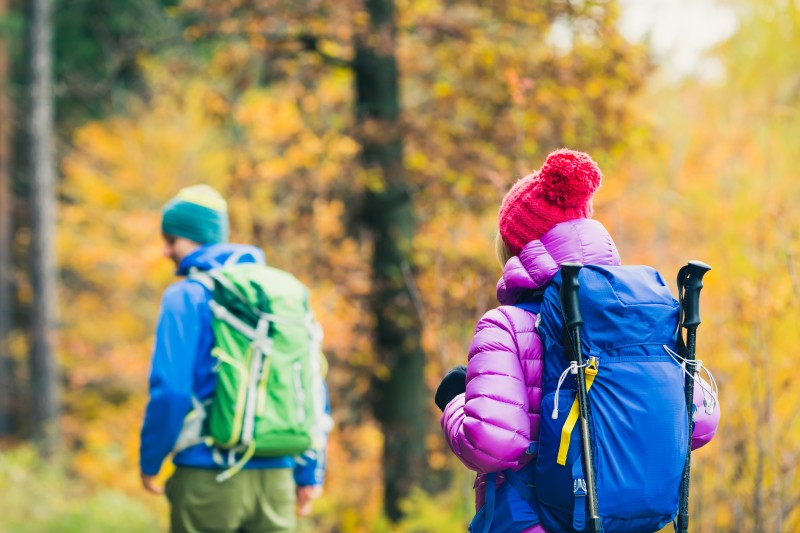 Man and woman happy couple hikers walking in autumn woods