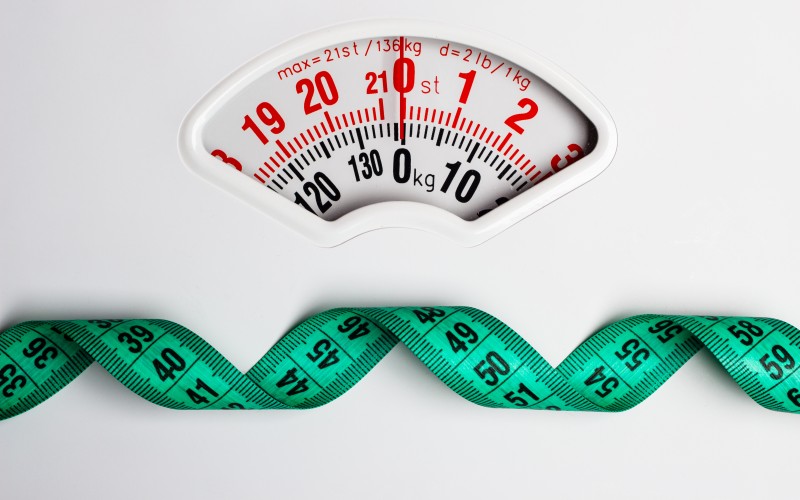 Green measuring tape on weight scale. Dieting