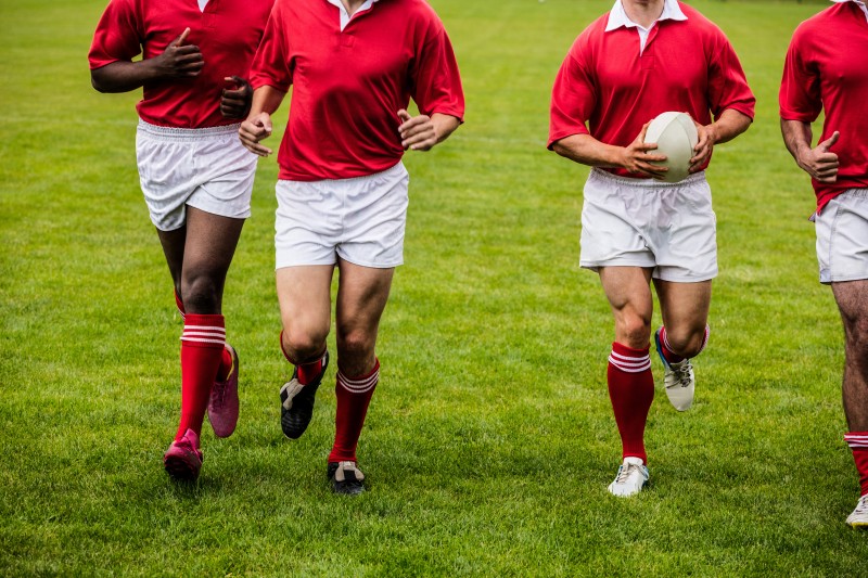 Rugby players jogging with ball at the park