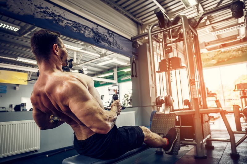 Strong Bodybuilder Doing Heavy Weight Exercise For Back On Machine