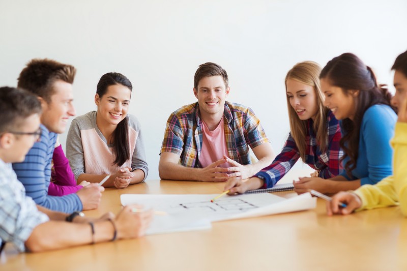 group of smiling students with blueprint