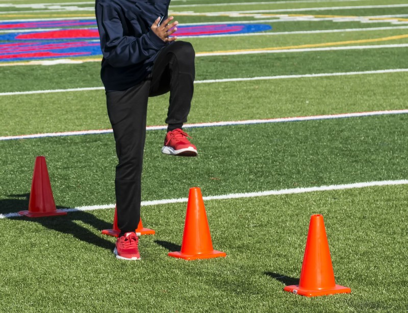 High school track athlete doing speed drills over cones