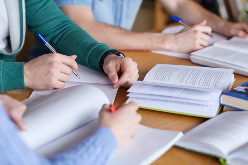 close up of hands with books writing to notebooks