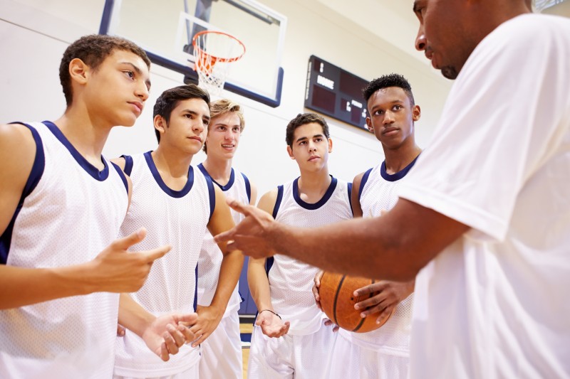 Male High School Basketball Team Having Team Talk With Coach