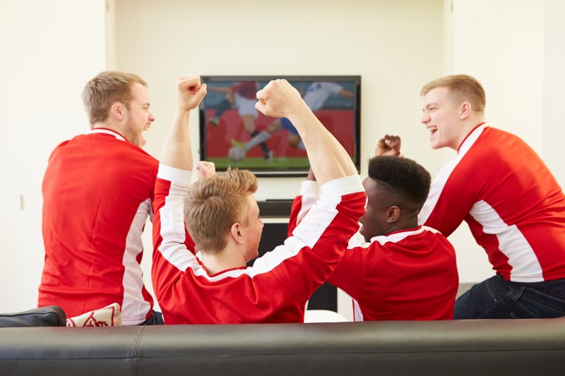 Group Of Sports Fans Watching Game On TV At Home