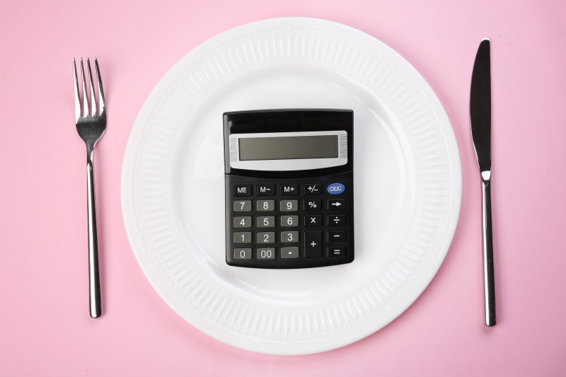 Diet concept. Plate with calculator and cutlery on color background