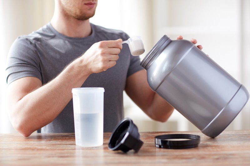 close up of man with protein shake bottle and jar
