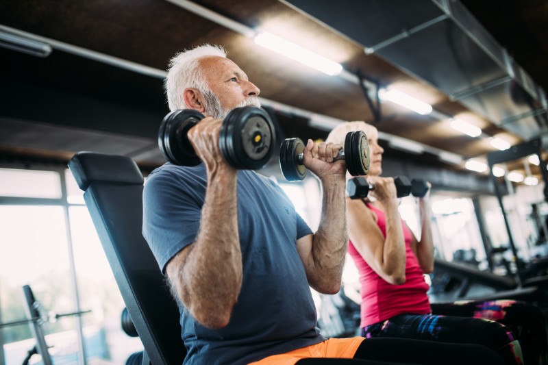 Mature fit couple exercising in gym to stay healthy