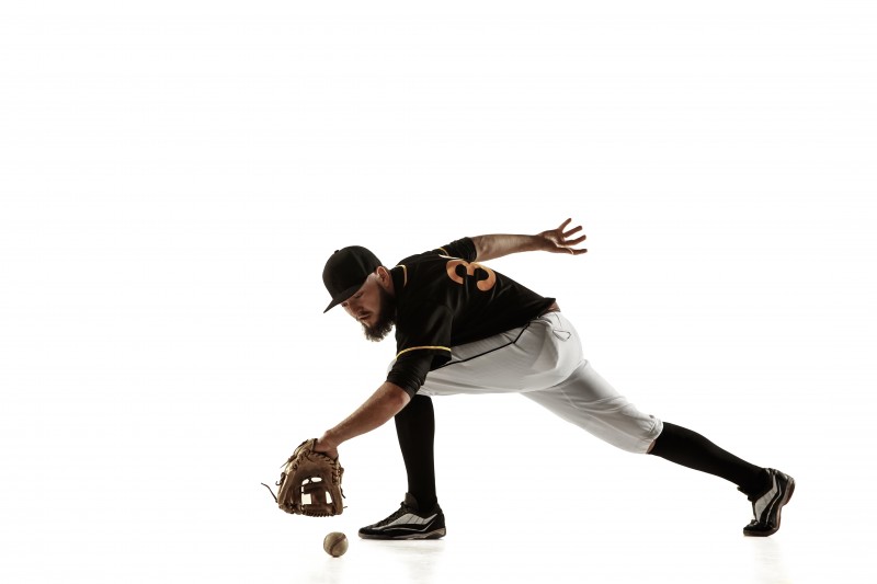 Baseball player, pitcher in a black uniform practicing on a white background.